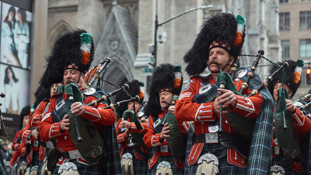 Bagpipers in green tartans, marching past St. Patrick&acirc;s Cathedral.